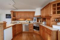 a kitchen with wooden cabinets and white appliances at Alpine View Apartments in Niedernsill