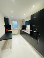 a kitchen with black cabinets and a white floor at Appartement Les Tilleuls &quot;3 étoiles&quot; in Niederbronn-les-Bains