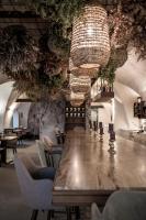 einen langen Tisch in einem Zimmer mit Stühlen und einem Kronleuchter in der Unterkunft Bogen bistro & apartments in Bozen