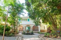 una casa blanca con árboles delante en Angeli Gardens Boutique Hotel, en San Pedro Sula
