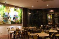 a restaurant with tables and chairs and a large painting on the wall at Hotel Eastern Bojonegoro in Bojonegoro