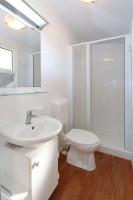 a white bathroom with a toilet and a sink at Poolside Mobile Home in Turanj