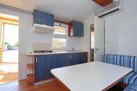 a kitchen with blue cabinets and a white table at Poolside Mobile Home in Turanj