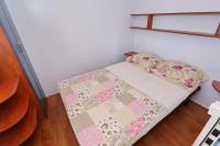 a small bedroom with a bed with a quilt on it at Poolside Mobile Home in Turanj