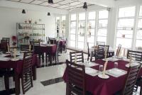 a dining room with tables and chairs and windows at Subhas Tourist Hotel in Jaffna