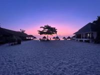 a beach with huts and a tree and a sunset at Nice Sea Resort in Srithanu