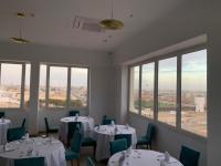 a dining room with tables and chairs and windows at Hotel Delphin-Nouadhibou in Nouadhibou