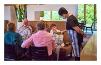 een groep mensen die rond een tafel wijn drinken bij Scenic Hotel Punakaiki in Punakaiki