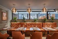 a dining room with a bench and tables and chairs at Bristol Hotel and Spa Bakuriani in Bakuriani