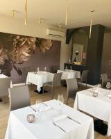 NarzoleにあるVILLA BERNASCONIの白いテーブルと椅子、そして花の壁画のあるレストラン