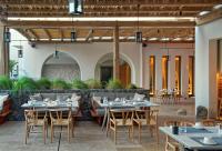 ein Restaurant mit Tischen und Stühlen und eine Terrasse in der Unterkunft Radisson Blu Zaffron Resort, Santorini in Kamari