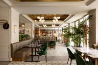 Fairmont Century Plaza Los Angeles at Beverly Hills في لوس أنجلوس: مطعم ذو كراسي خضراء وطاولات