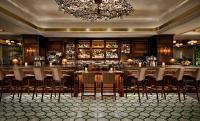 Fairmont Century Plaza Los Angeles at Beverly Hills في لوس أنجلوس: مطعم فيه بار فيه كراسي وثريا