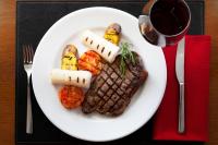 un plato de comida con carne y verduras y una copa de vino en Novotel Sao Jose dos Campos, en São José dos Campos