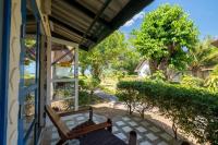 a porch with two wooden chairs and a tree at Gooddays Lanta Beach Resort SHA in Ko Lanta