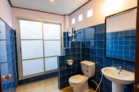 a blue tiled bathroom with a toilet and a sink at Gooddays Lanta Beach Resort SHA in Ko Lanta