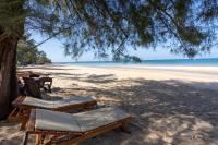 a beach with chairs and a tree and the ocean at Gooddays Lanta Beach Resort SHA in Ko Lanta