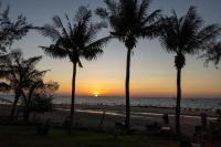 a sunset at the beach with palm trees at Gooddays Lanta Beach Resort SHA in Ko Lanta