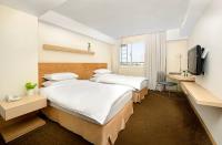 a hotel room with two beds and a television at Beacon Hotel in Taichung