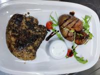 a white plate with a piece of meat and vegetables at Hotel FAMIL - adults only in Bansko