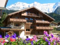 a large wooden building with mountains in the background at Alpine Lodge 5 in Les Contamines-Montjoie