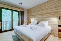 a bedroom with a large white bed and a large window at Chalet La Mésange Boréale in Morzine