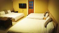 a hotel room with two beds and a tv at Camellia B&amp;B in Taitung City