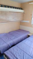 two beds in a small room with purple sheets at mobil-home du lac de Foix in Foix