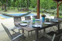 a wooden table and chairs on a deck with a hammock at holiday home, Grayan-et-l&#39;Hôpital in Grayan-et-lʼHôpital