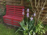 a red bench sitting next to a fence with purple flowers at Jolie maison atypique à Montrichard in Montrichard