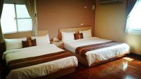 a hotel room with two beds and two windows at Camellia B&amp;B in Taitung City