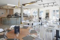 洛格罗尼奥Iraipe Logroño Hotel的一间有白色桌椅和酒吧的餐厅