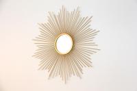 a gold sunburst mirror on a white wall at Le Lac d&#39;Or - Duke Housing in Créteil