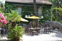 a restaurant with tables and chairs with a giraffe standing in the yard at Hostellerie Le Paradou in Lourmarin