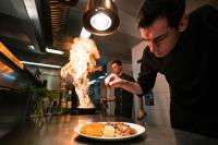 un hombre en una cocina preparando un plato de comida en Hotel Swiss Star, en Wetzikon