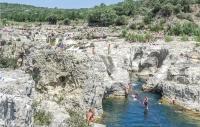 a group of people swimming in a river between rocks at Amazing Home In Barjac With 3 Bedrooms, Wifi And Outdoor Swimming Pool in Barjac