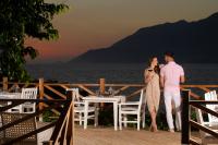 un uomo e una donna in piedi su un ponte con un tavolo di Peninsula Gardens Hotel a Kaş