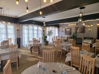 Un restaurante con mesas y sillas blancas y ventanas. en Le Chalet Montégut, en Moulins