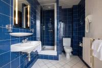 a blue tiled bathroom with a sink and a toilet at Bijou Hôtel Paris Boulogne in Boulogne-Billancourt