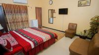 a bedroom with a bed and a chair and a table at Seasons Inn in Karachi