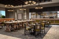 a restaurant with tables and chairs and a kitchen at Crowne Plaza North Augusta, by IHG in North Augusta