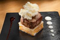 Un trozo de pastel en un plato negro con crema batida en Hotel Colón Gran Meliá - The Leading Hotels of the World, en Sevilla