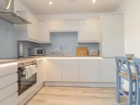 a kitchen with white cabinets and a blue wall at Mews House in Camborne