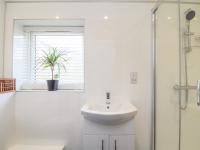 a white bathroom with a sink and a window at Mews House in Camborne