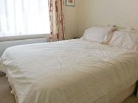 a white bed in a bedroom with a window at Joylands in Budock Water