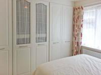 a white bedroom with white cabinets and a bed at Joylands in Budock Water