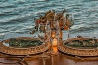 una mesa con dos platos y copas de vino en la playa en Khaban Bacalar Hotel Boutique, en Bacalar