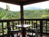 a table and chairs on a balcony with mountains in the background at Ji Ji Farm Homestay in Jiji