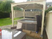 a hot tub under a gazebo on a patio at Garden Suite in Rhuddlan