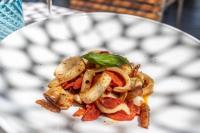 Un plato blanco con un sándwich con pimientos y cebollas. en Vistamare Suite, en Lido di Savio